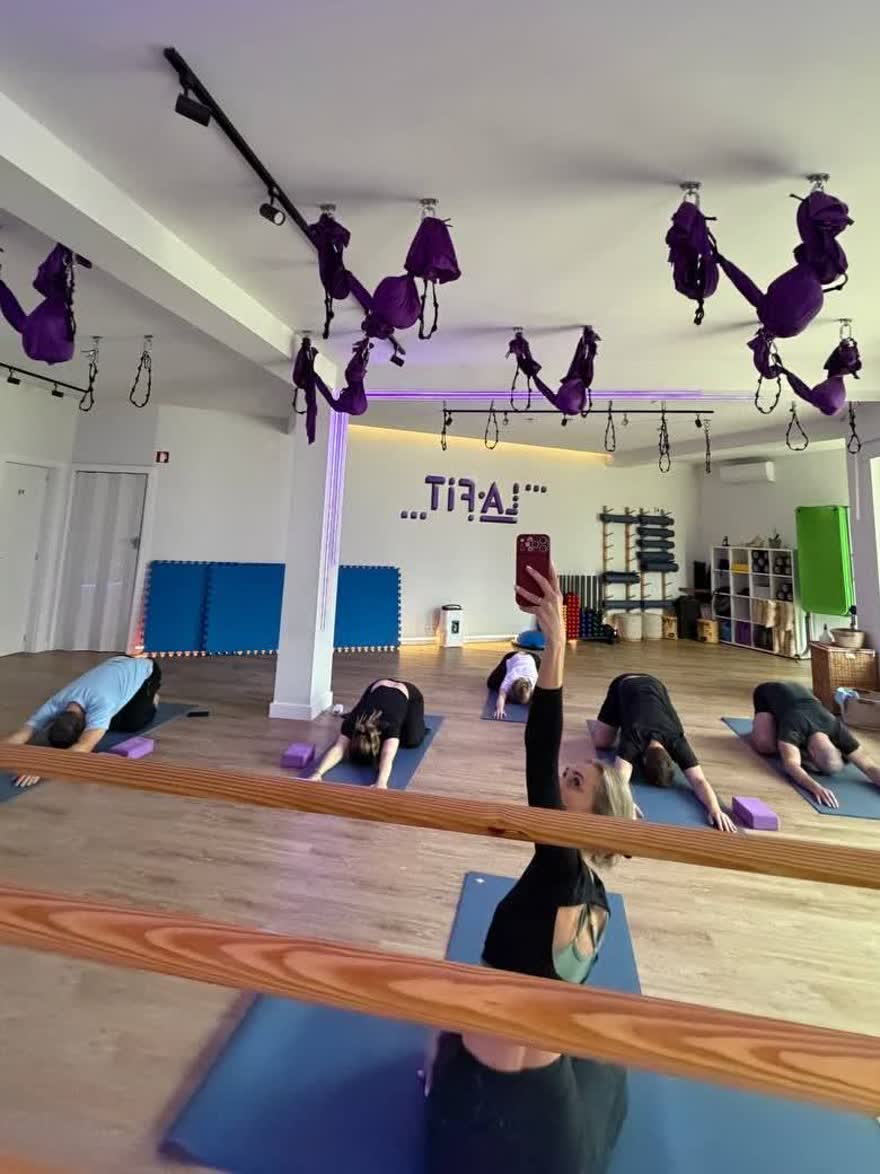 Група в позі дитини на килимках у студії LA fit, гамаки над головою